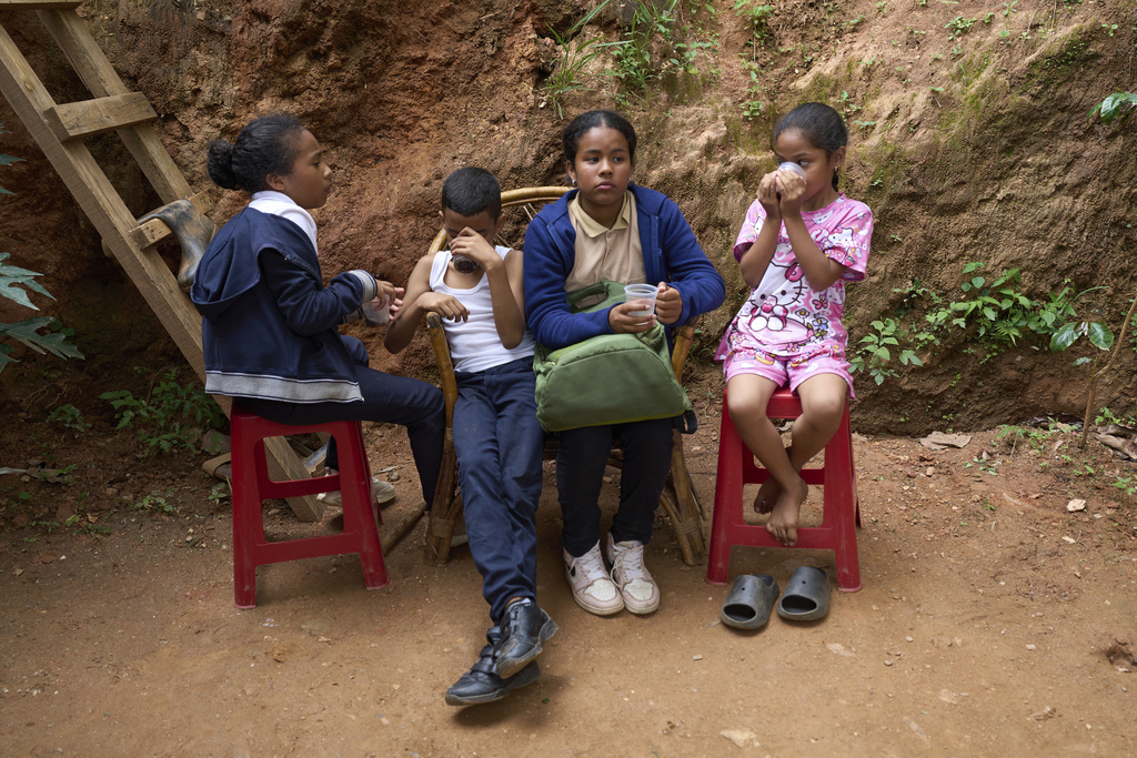 Children drink sodas after carrying groceries and vegetables at a church-run soup kitchen that feeds school children in La Vega, on the outskirts of Caracas, Venezuela, Wednesday, July 2, 2025. (AP Photo/Ariana Cubillos)