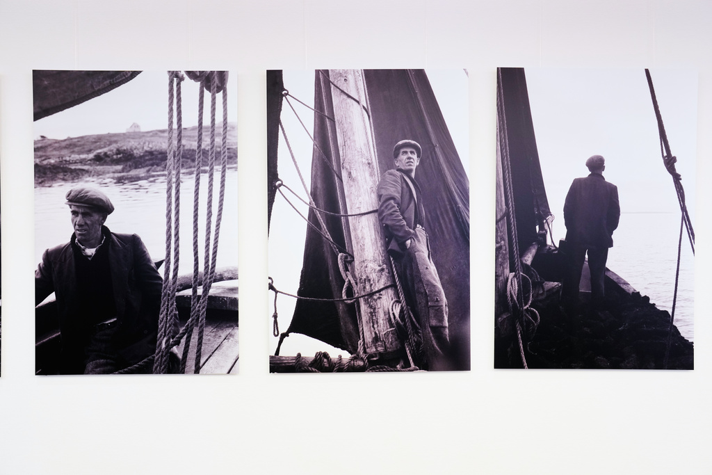 Photos of man on a sailing ship with peat taken by Diether Endlicher, a former photographer of The Associated Press, in Ireland in 1963 at the exhibition Ireland In The Frame, at the Irish embassy in Berlin, Germany, Saturday, Nov. 22, 2025. (AP Photo/Markus Schreiber)