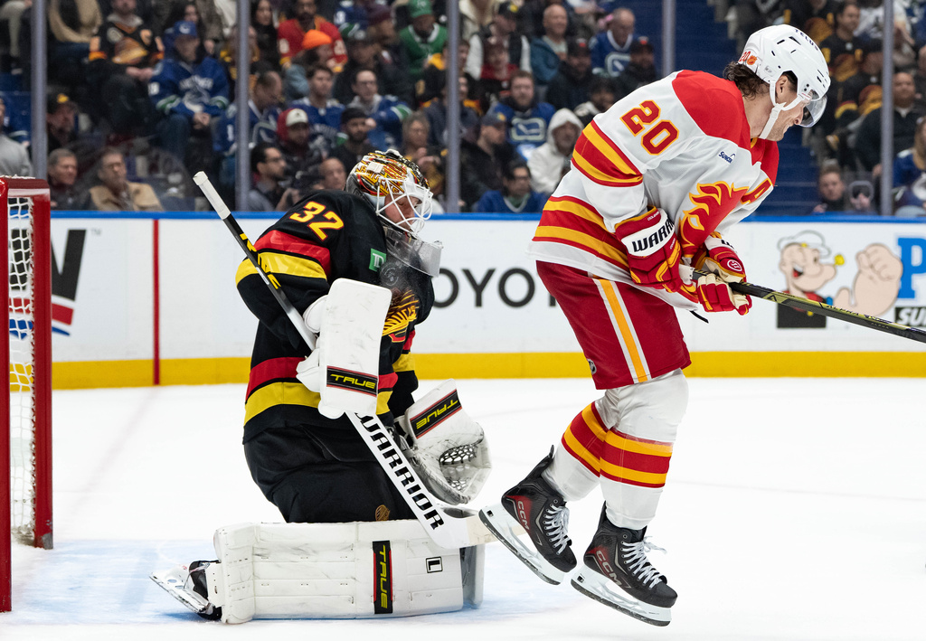 Vancouver Canucks goaltender Kevin Lankinen (32) stops the puck as Calgary Flames' Blake Coleman (20) jumps during second period of an NHL game in Vancouver, British Columbia, on Sunday, Nov. 23, 2025. (Ethan Cairns/The Canadian Press via AP)