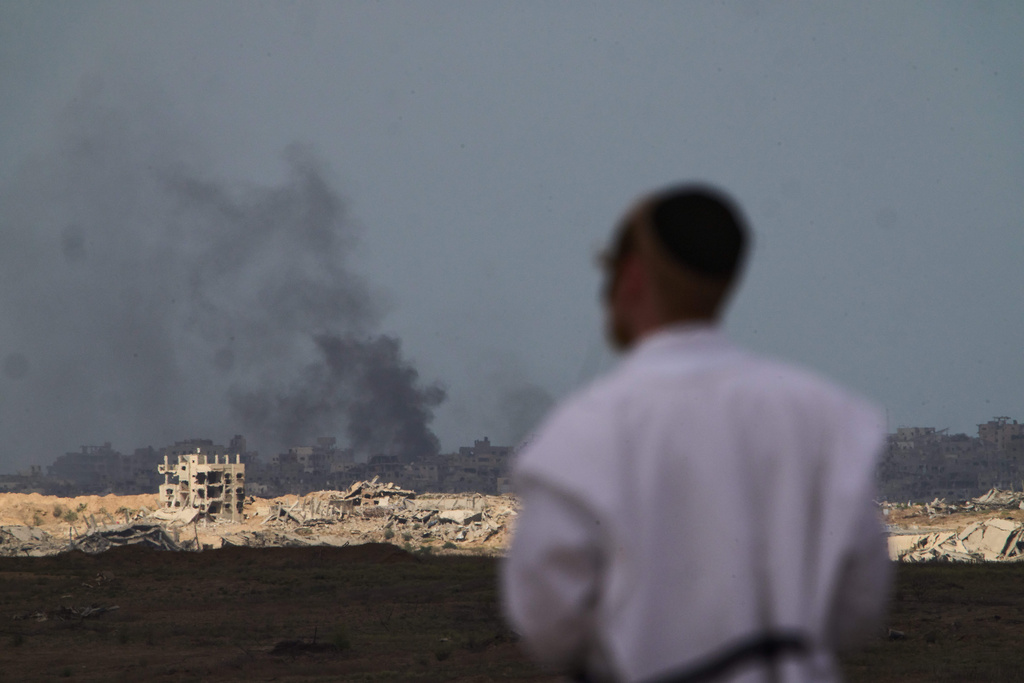 A Jewish man watches smoke rise in the sky after an explosion in the Gaza Strip, as seen from southern Israel, Thursday, Oct. 9, 2025, following the announcement that Israel and Hamas have agreed to the first phase of a peace plan to pause the fighting. (AP Photo/Ariel Schalit)