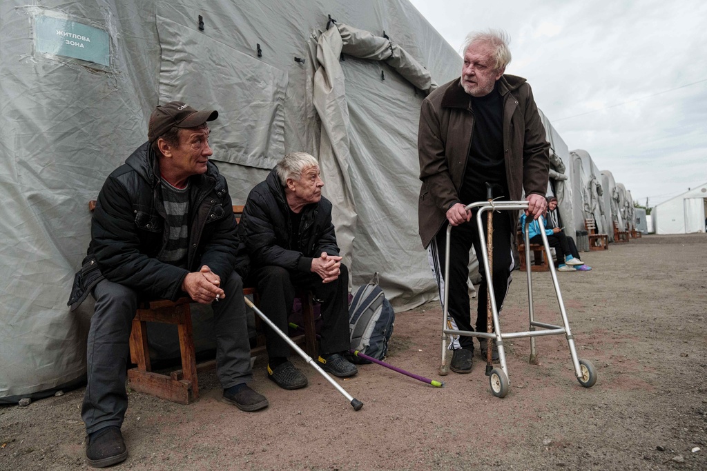 Men rest and talk at a center for displaced persons, after they evacuated from settlements on the frontline, in Pavlohrad, Ukraine, Wednesday, Oct. 8, 2025. (AP Photo/Evgeniy Maloletka)