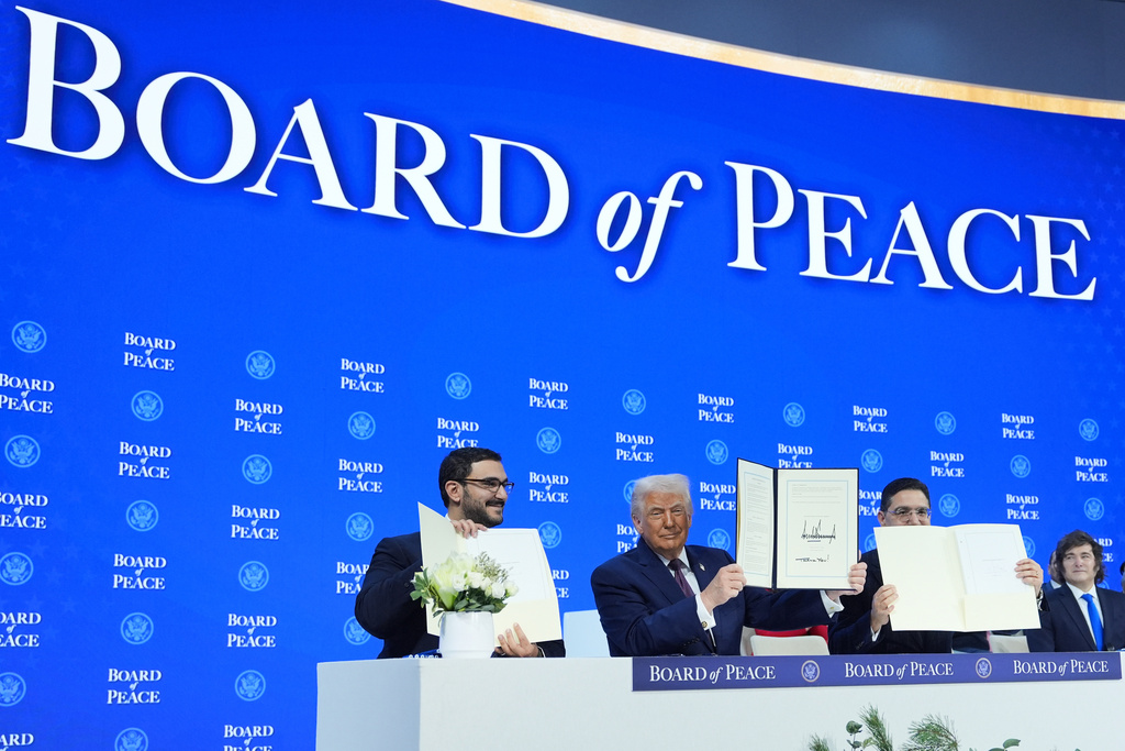 President Donald Trump, center, holds up a signed Board of Peace charter during the Annual Meeting of the World Economic Forum in Davos, Switzerland, Thursday, Jan. 22, 2026. (AP Photo/Evan Vucci)