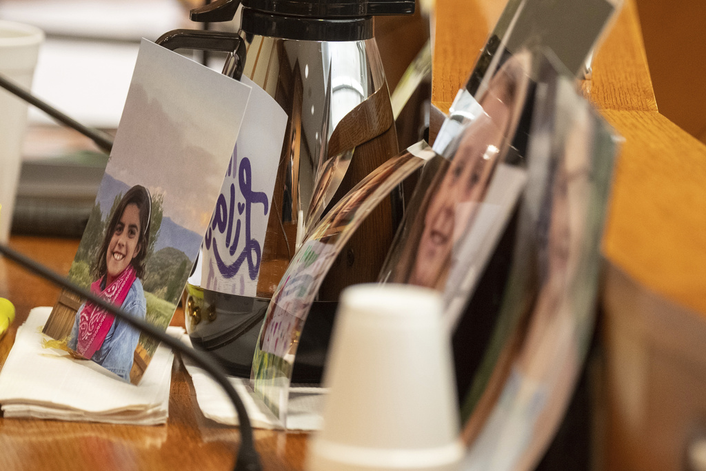 Camp Mystic flood victim photos are seen on a lawmaker's desk as families testify in front of the Senate Disaster Preparedness and Flooding committee at the Texas Capitol in Austin, Wednesday, Aug. 20, 2025. (Mikala Compton/Austin American-Statesman via AP)