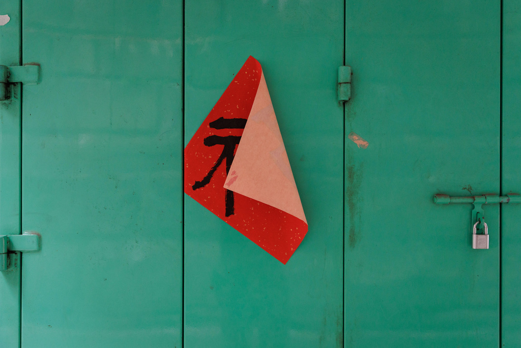 A couplet with the Chinese character "good fortune" is half peeled off on a green metal door in Hong Kong, Feb. 9, 2026. (AP Photo/May James)