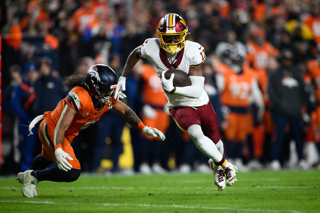 Washington Commanders wide receiver Terry McLaurin (17) runs past Denver Broncos safety Talanoa Hufanga during the first half of an NFL football game Sunday, Nov. 30, 2025, in Landover, Md. (AP Photo/Nick Wass)
