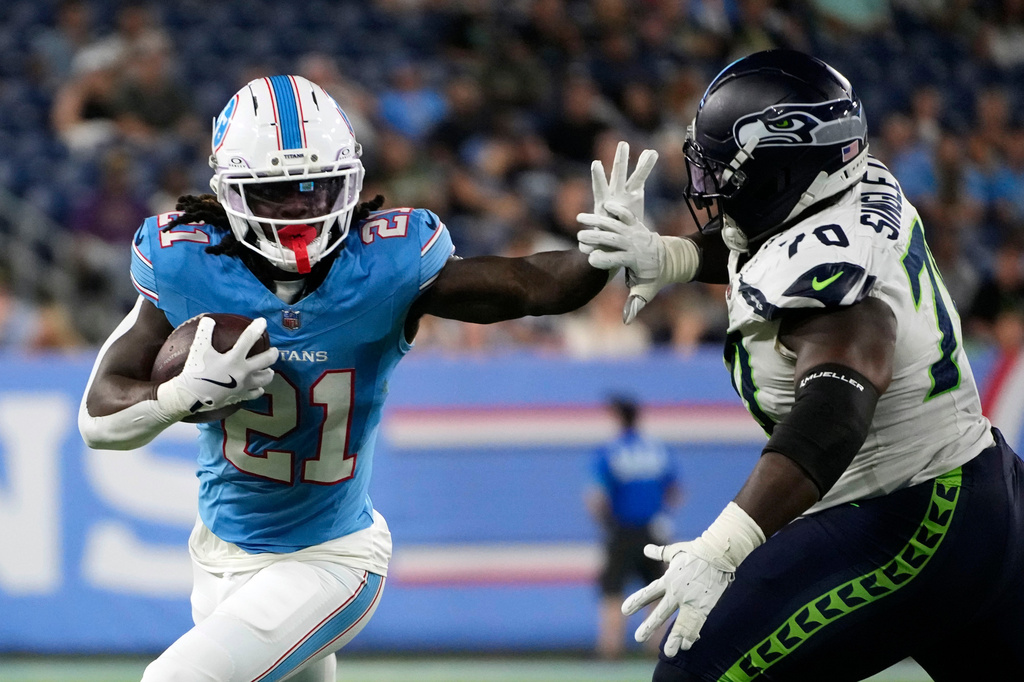 Tennessee Titans running back Dominic Richardson (21) runs from Seattle Seahawks defensive tackle J.R. Singleton (70) during the second half of a preseason NFL football game, Sunday, Aug. 23, 2026, in Nashville, Tenn. (AP Photo/George Walker IV)