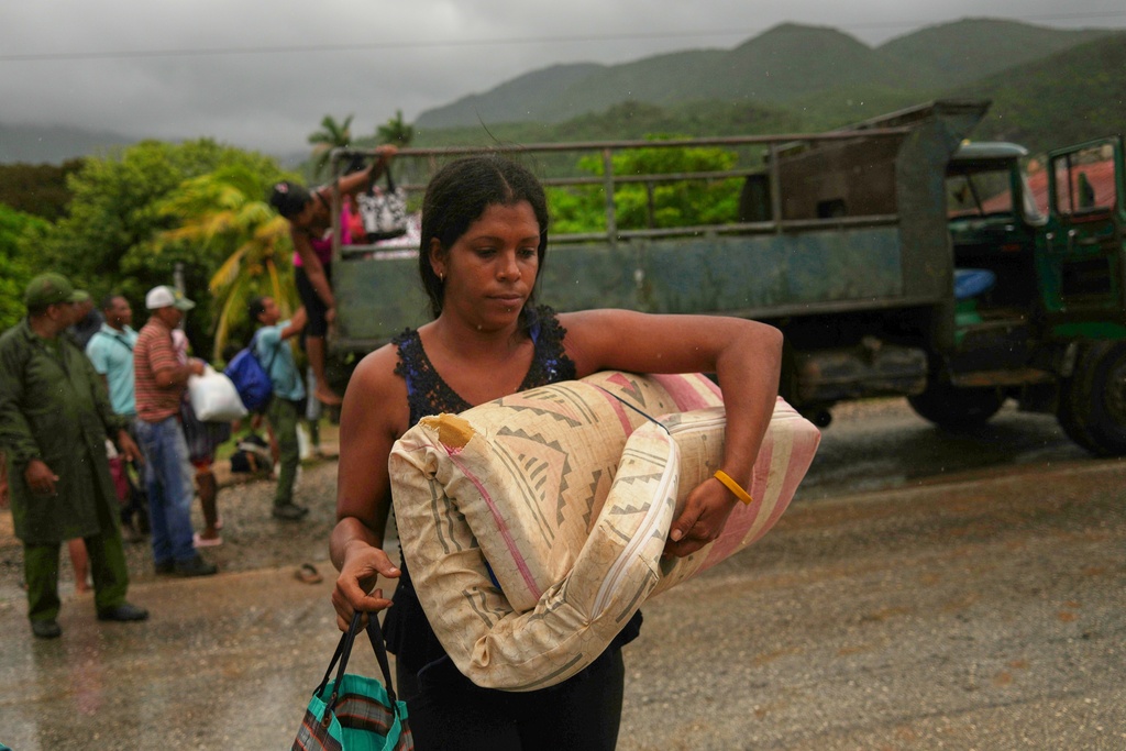 A woman carrying a mattress in the rain evacuates before the arrival of Hurricane Melissa in Cañizo, a community in Santiago de Cuba, Tuesday, Oct. 28, 2025. (AP Photo/Ramón Espinosa)