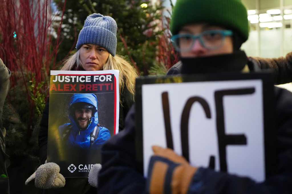 Demonstrator holds signs during a protest outside the office of Sen. Amy Klobuchar, D-Minn., on Monday, Jan. 26, 2026, in Minneapolis, after Alex Pretti was fatally shot by a U.S. Border Patrol officer over the weekend. (AP Photo/Adam Gray)