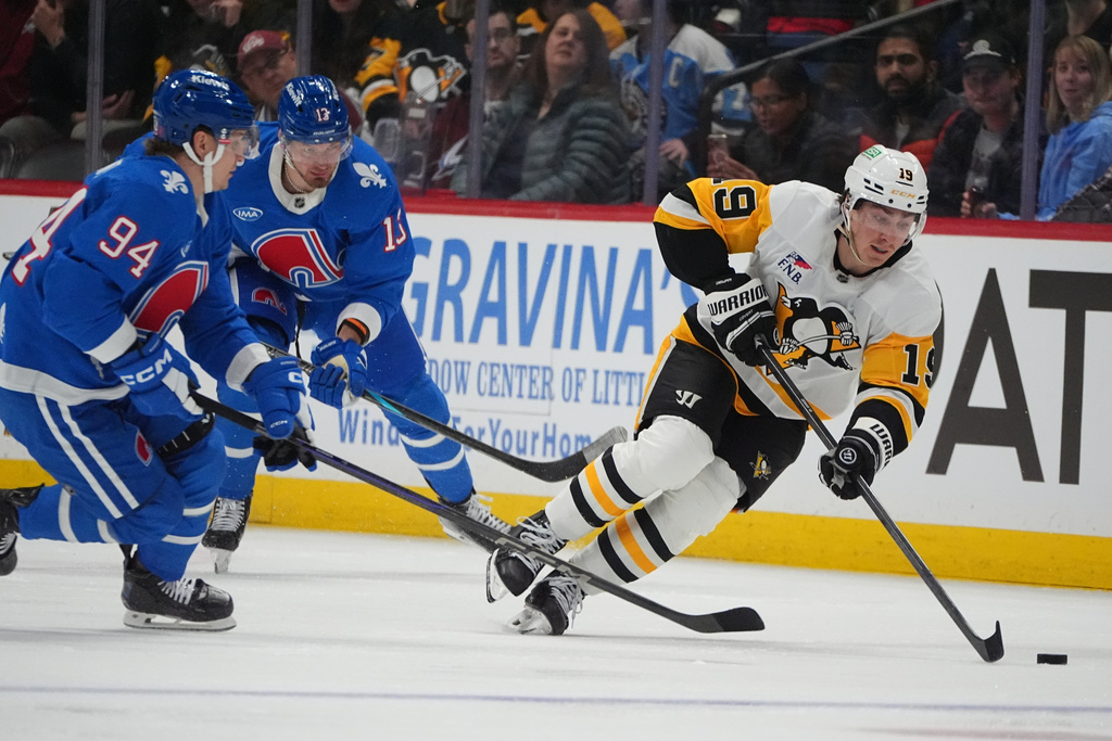 Pittsburgh Penguins center Connor Dewar, right, collects the puck as Colorado Avalanche left wing Joel Kiviranta (94) and right wing Valeri Nichushkin, back left, defend in the second period of an NHL hockey game Monday, March 16, 2026, in Denver. (AP Photo/David Zalubowski)