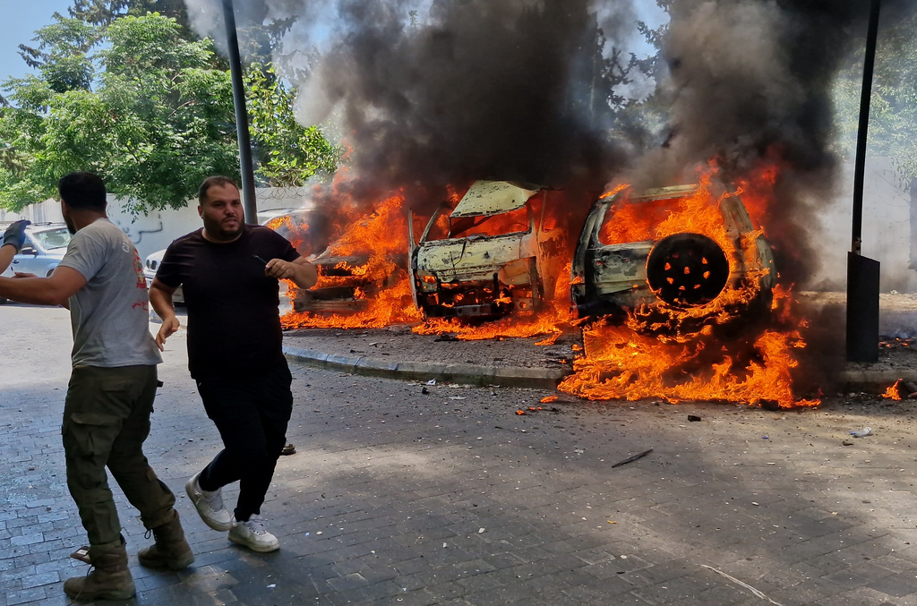 A man runs past burning cars following an Israeli airstrike in the southern port city of Sidon, Lebanon, Wednesday, June 10, 2026. (AP Photo/Mohammed Zaatari)