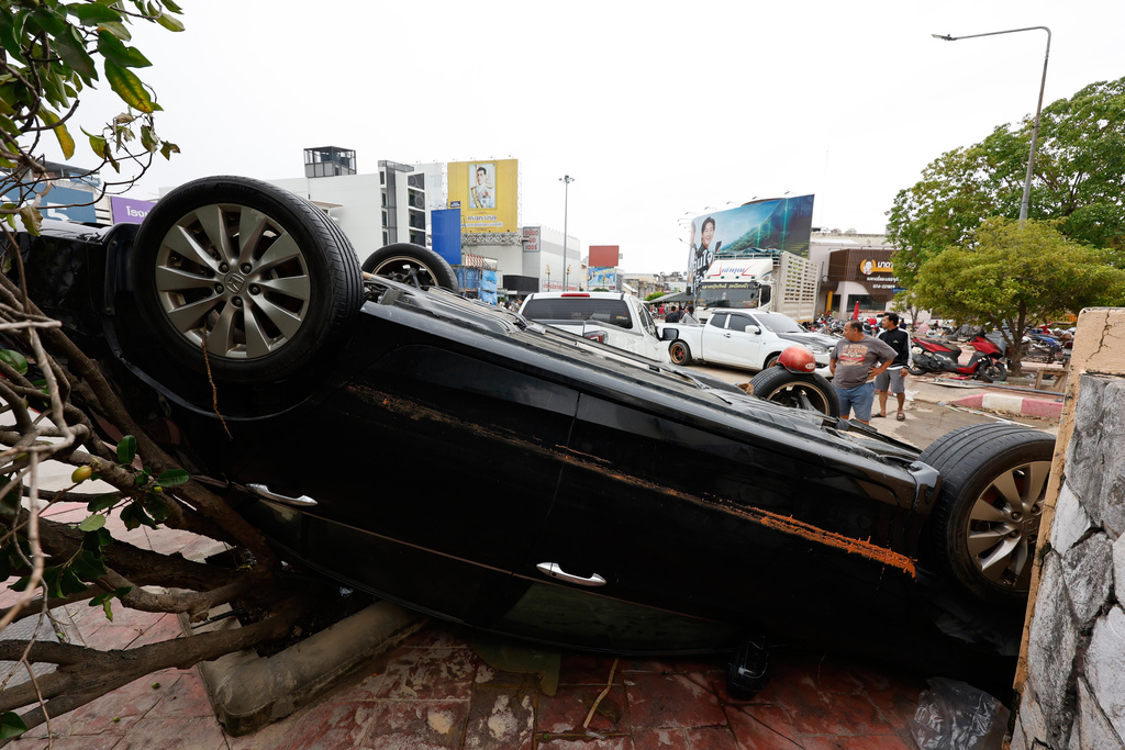 A man stands behind a damaged car following floods in Songkhla province, southern Thailand, Friday, Nov. 28, 2025. (AP Photo/Sarot Meksophawannakul)