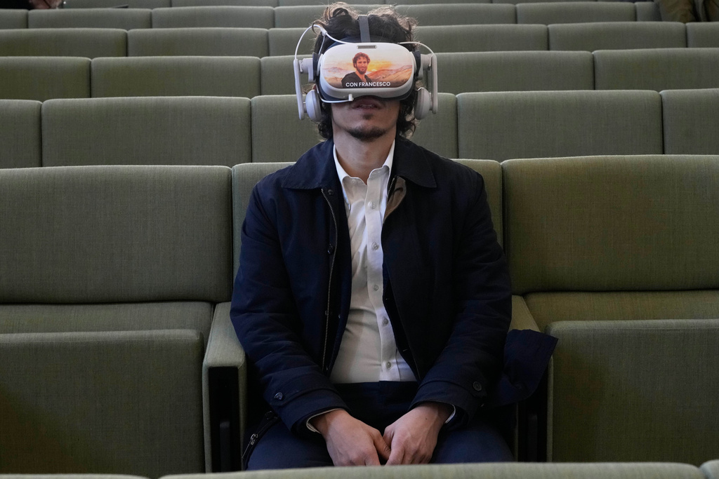 A journalist wears a 3D visor projecting scenes from the life of St. Francis during the first public display of the saint’s bones inside the Basilica of St. Francis, marking the 800th anniversary of his death, in Assisi, Italy, Sunday, Feb. 22, 2026. (AP Photo/Gregorio Borgia)