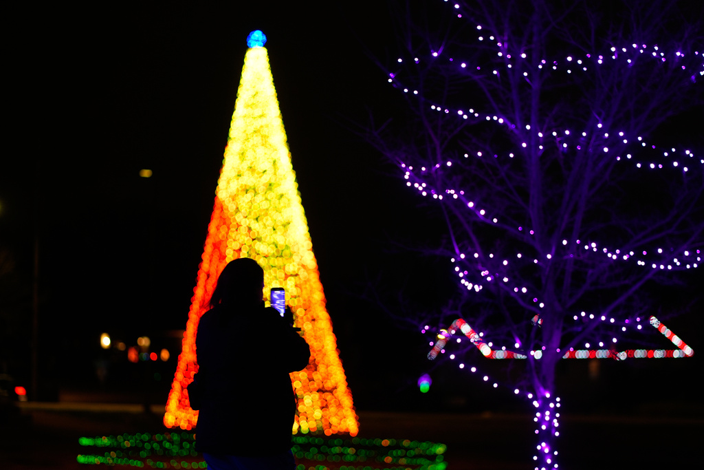 A person takes a photo of holiday lights, Wednesday, Dec. 10, 2025, at a park in Lenexa, Kan. (AP Photo/Charlie Riedel)