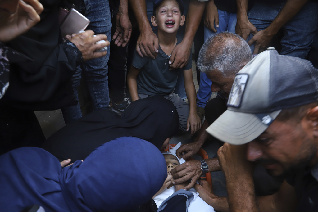 Palestinian relatives mourn over the body of 13-year-old Karim Qdeih, who was killed along with others in overnight Israeli strikes, during his funeral outside Nasser Hospital in Khan Younis, southern Gaza Strip, Saturday, Aug. 23, 2025. (AP Photo/Mariam Dagga)