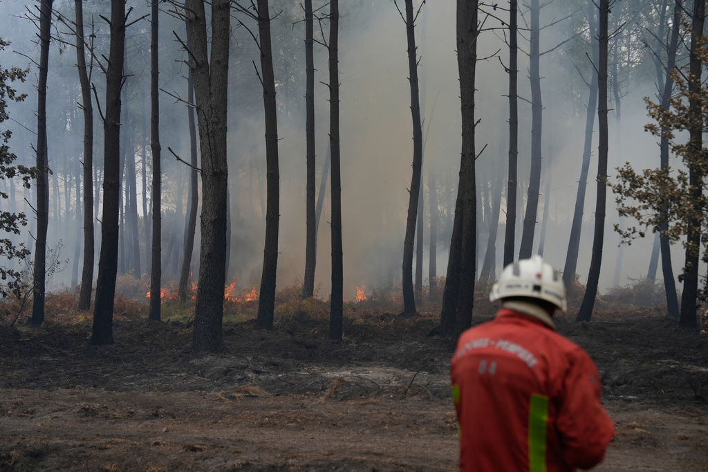 A firefighter works to extinguish a fire, near Blagon, southwestern France, Friday, July 31, 2026. (AP Photo/Baz Ratner)