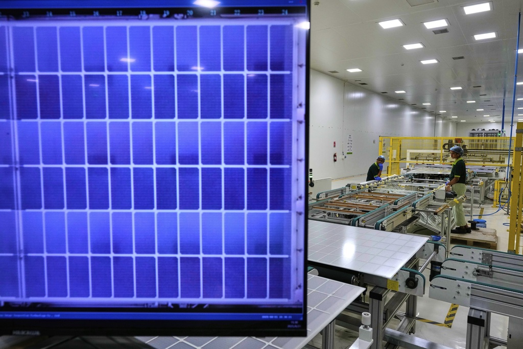 Workers monitor and check solar panels for tagging as they pass through a machine at a ReNew manufacturing plant on the outskirts of Jaipur, India, Thursday, Aug. 21, 2025. (AP Photo/Manish Swarup)