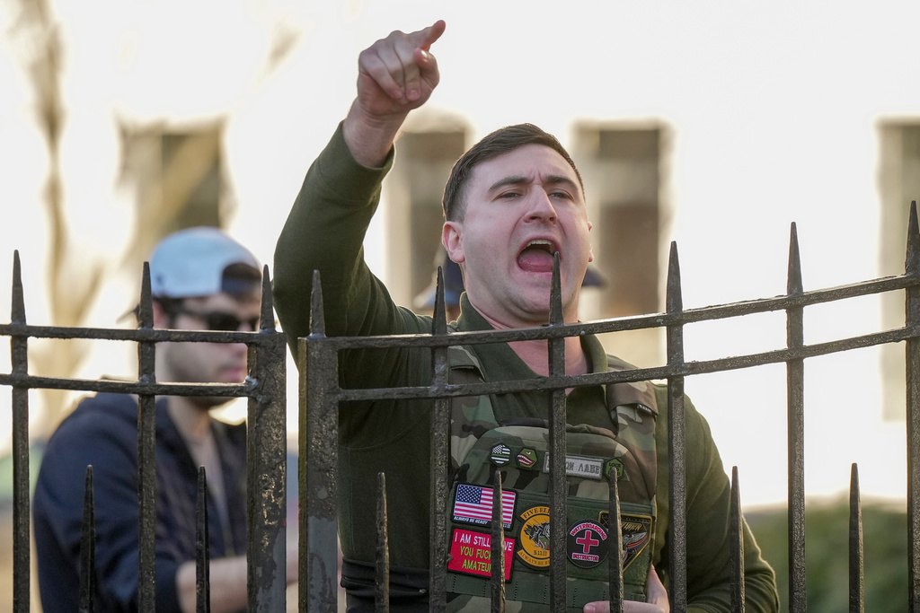 Jake Lang shouts from a sidewalk as New York Mayor Zohran Mamdani speaks during a news conference at Gracie Mansion, Monday, March 9, 2026, in New York. (AP Photo/Angelina Katsanis)