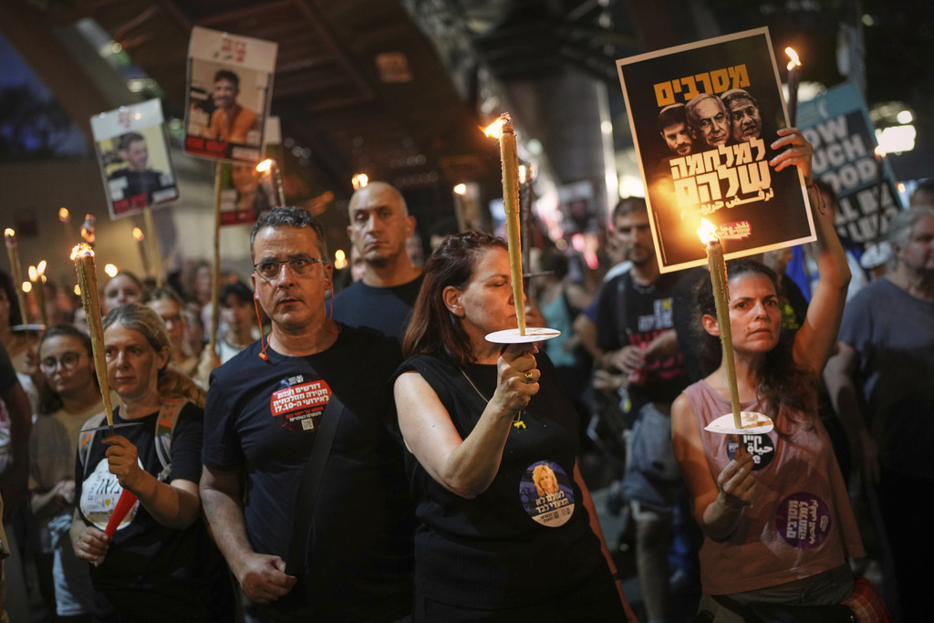 Demonstrators light torches during a protest demanding the release of all hostages held by Hamas in the Gaza Strip and calling for an end to the war, in Tel Aviv, Israel, Saturday, Aug. 9, 2025. (AP Photo/Ohad Zwigenberg)