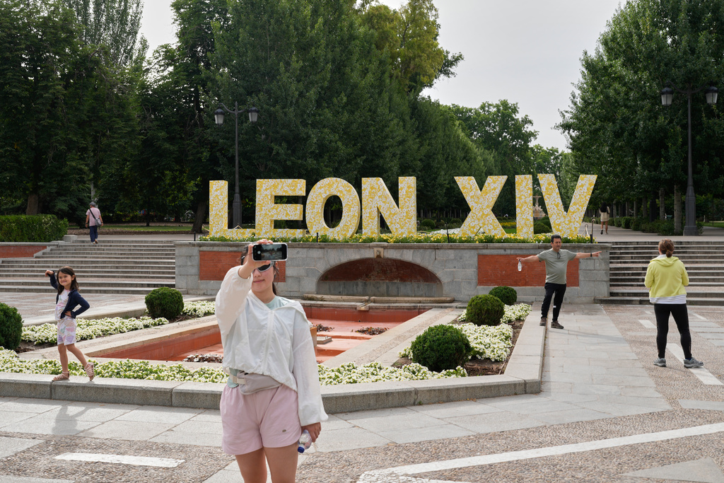 Visitors pose for photos beside a sign bearing the name of Pope Leo XIV in Madrid, Spain, Saturday, June 6, 2026. (AP Photo/Bernat Armangue)