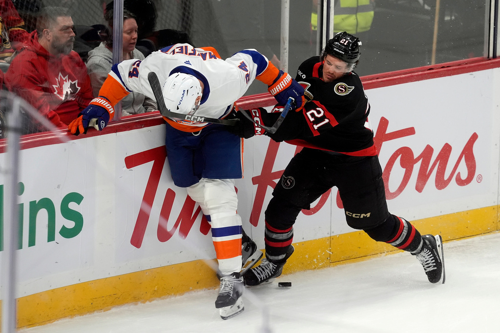 Ottawa Senators center Nick Cousins (21) gets his stick up on New York Islanders' Scott Mayfield (24) for a penalty during the first period of an NHL hockey game in Ottawa, Ontario, Saturday, Oct. 18, 2025. (Adrian Wyld/The Canadian Press via AP)