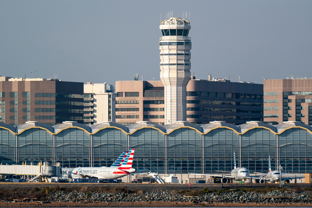 FILE - Passenger planes rest in front of a control tower at the Reagan National Airport in Washington, Nov. 11, 2021. (AP Photo/J. Scott Applewhite, File)