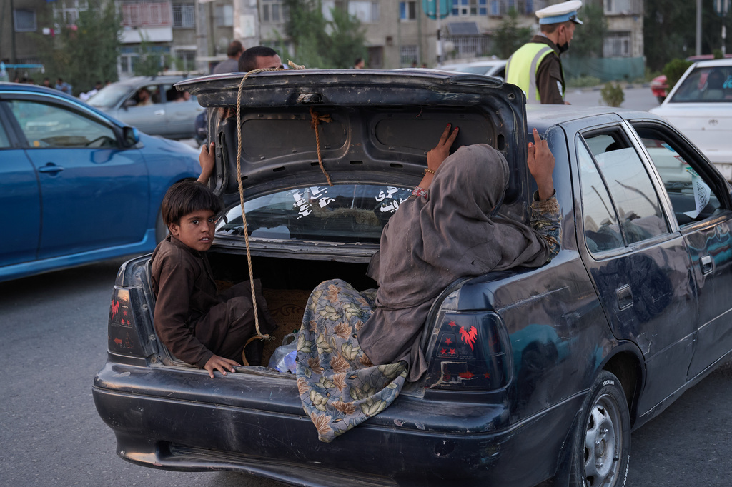 A boy and a woman ride in the open trunk of a car on the eve of the fifth anniversary of the U.S. withdrawal and the start of Taliban rule in Kabul, Afghanistan, Friday, Aug. 14, 2026. (AP Photo/Nava Jamshidi)