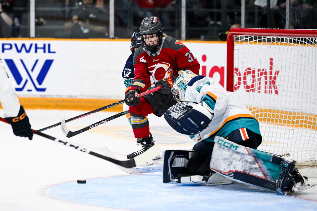 Ottawa Charge's Rebecca Leslie (37) tries to gain control of the puck in front of New York Sirens' goaltender Kayle Osborne (82) during the first period a PWHL hockey game in Ottawa, Ontario, Saturday, April 18, 2026. (Spencer Colby/The Canadian Press via AP)