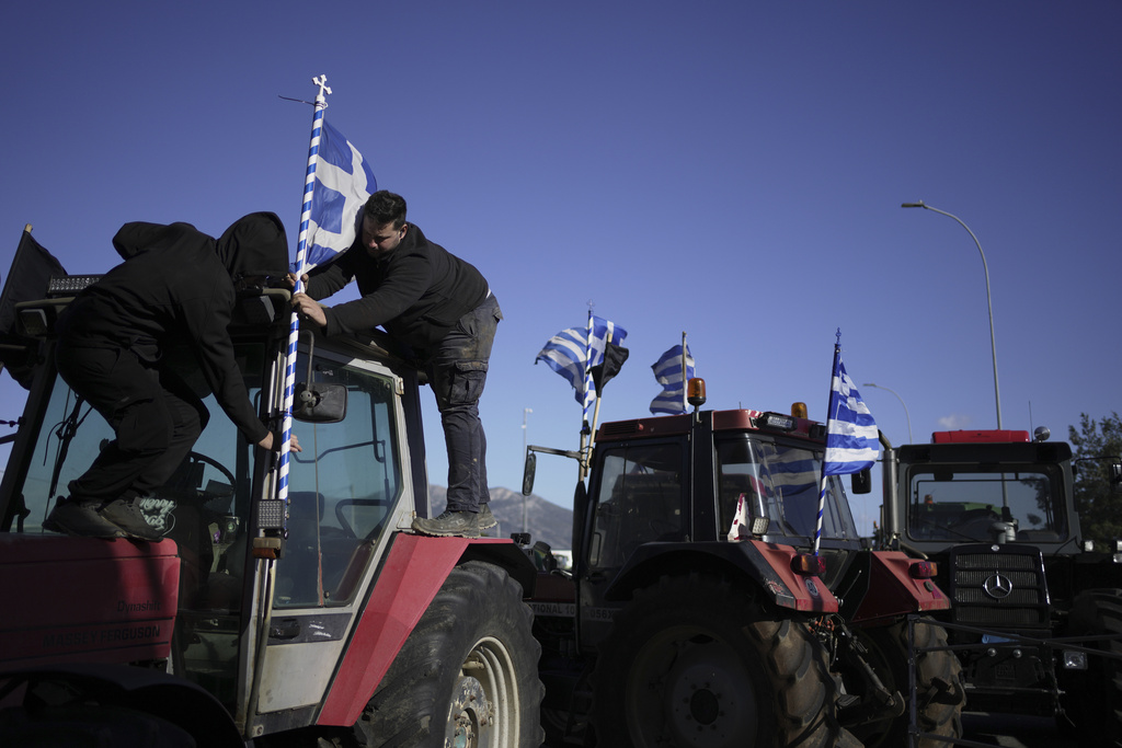 Farmers place a Greek flag on a tractor blocking the highway during a protest in Thiva, about 70 kilometers (44 miles) north of Athens, Greece, over delays in the payment of European Union-backed agricultural subsidies, Thursday, Jan. 8 2025. (AP Photo/Thanassis Stavrakis)
