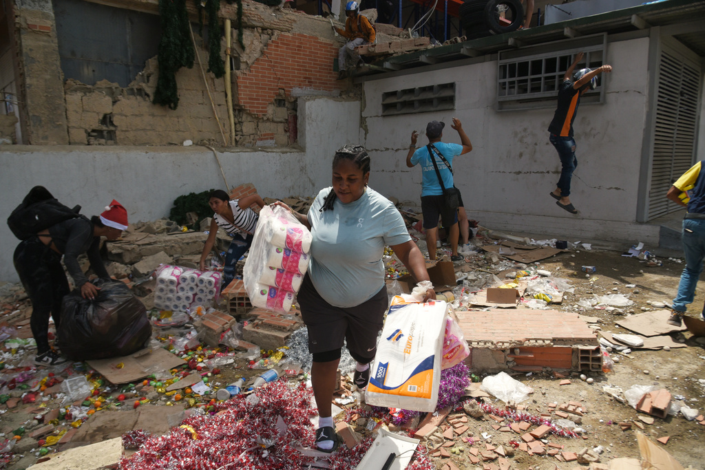 People take goods from damaged stores a day after earthquakes and aftershocks struck Catia La Mar, Venezuela, Thursday, June 25, 2026. (AP Photo/Jonathan Lanza)