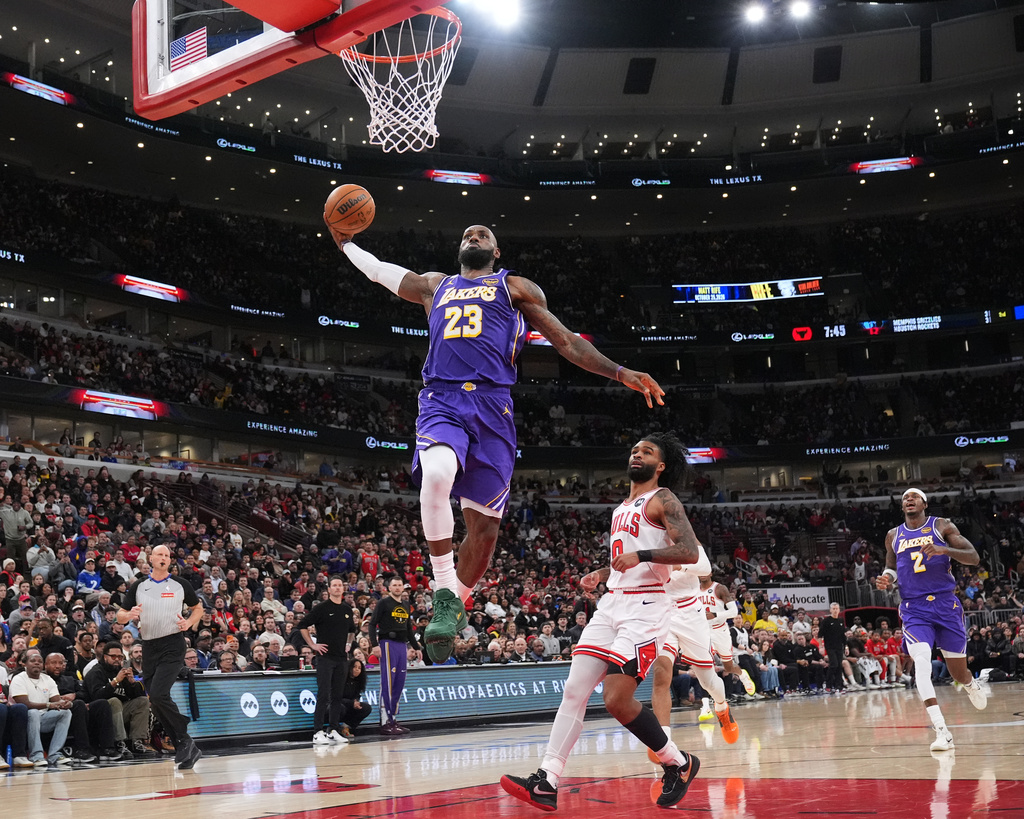 Los Angeles Lakers forward LeBron James, left, goes up for a dunk as Chicago Bulls guard Coby White looks on during the first half of an NBA basketball game in Chicago, Monday, Jan. 26, 2026. (AP Photo/Nam Y. Huh)