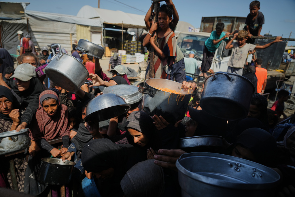 Palestinians struggle to get donated food at a community kitchen in Khan Younis, southern Gaza Strip, Sunday, Oct. 5, 2025. (AP Photo/Jehad Alshrafi)