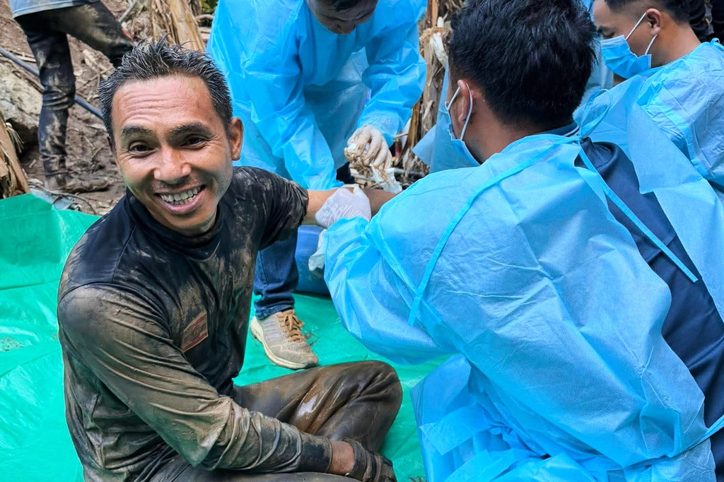 In this image released by Metta Tham Rescue Kalasin, rescuers, left, sit after rescuing people who have been trapped in a cave in Xaisomboun province, Laos. Wednesday, May 27, 2026. (Metta Tham Rescue Kalasin via AP)