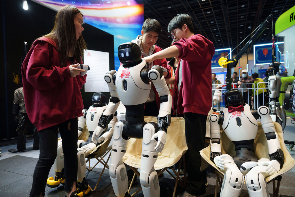 Workers prepare humanoid robots for a performance at a trade fair in Beijing, China, Wednesday, Feb. 18, 2026. (AP Photo/Vincent Thian)