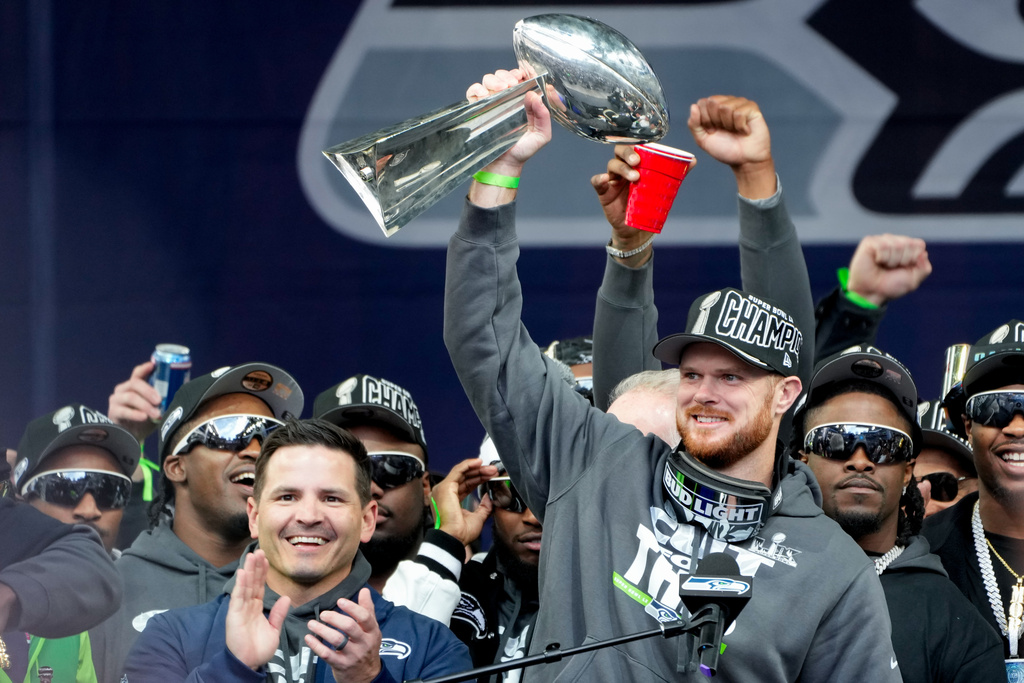 Seattle Seahawks quarterback Sam Darnold holds the Lombardi Trophy as head coach Mike MacDonald celebrates at left during the team's NFL football Super Bowl 60 celebration at Lumen Field, Wednesday, Feb. 11, 2026, in Seattle. (AP Photo/Stephen Brashear)