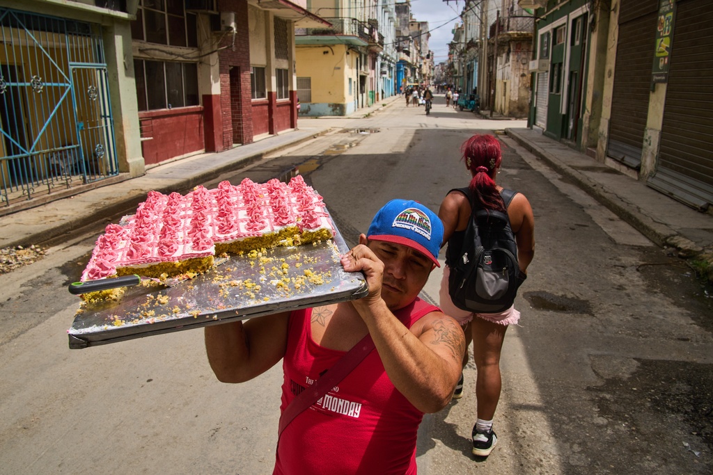 A street vendor selling pastries walks down the middle of the street looking for customers in Havana, Cuba, Thursday, March 19, 2026. (AP Photo/Ramon Espinosa)