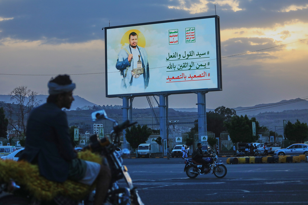 People ride their motorbikes under a billboard showing Houthi leader Abdul Malik al-Houthi with a phrase that reads in Arabic; "master of words and deeds" in Sanaa, Yemen, Monday, Sept. 21, 2026. (AP Photo/Osamah Abdulrahman)