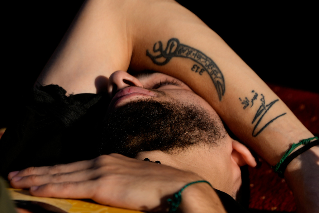 A Hezbollah supporter with a tattoo on his arm showing the signature of late Hezbollah leader Sayyed Hassan Nasrallah, lies on the ground as he listens to the death story of Imam Hussein during the holy day of Ashoura that commemorates the 7th century martyrdom of the Prophet Muhammad's grandson Hussein, in Dahiyeh, Beirut's southern suburbs, Lebanon, Friday, June 26, 2026. (AP Photo/Hussein Malla)