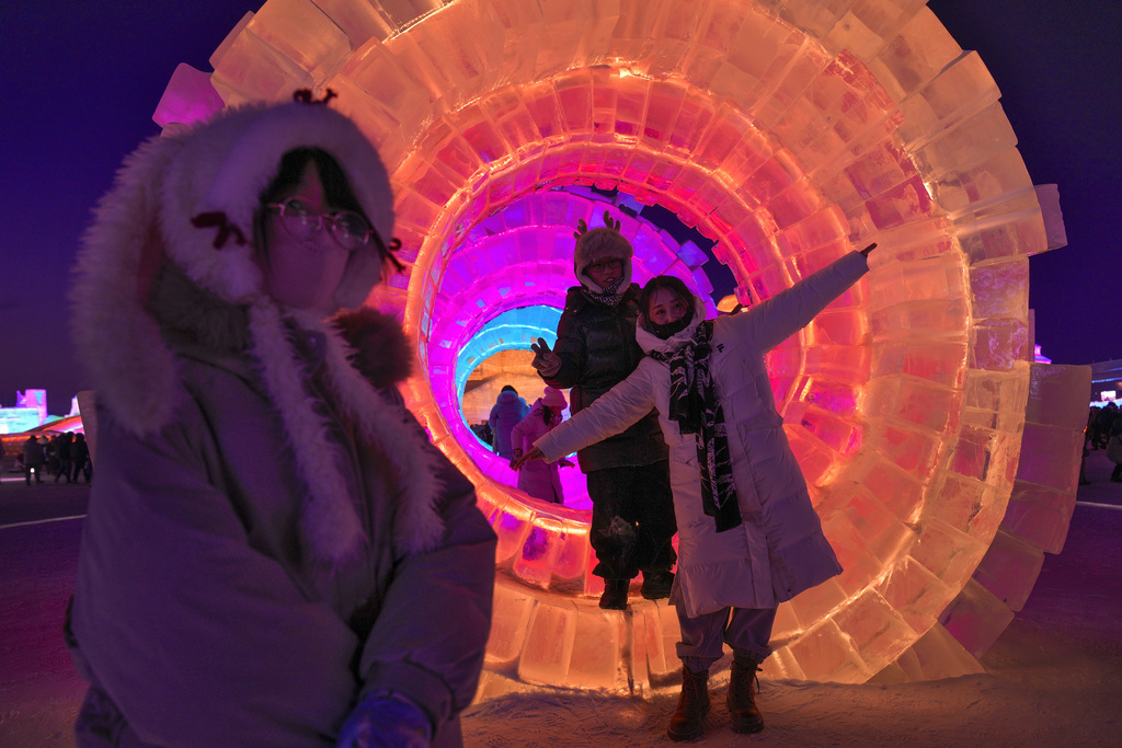 Visitors take pictures with the illuminated ice structures at the Harbin Ice and Snow World in Harbin, China's Heilongjiang province on Sunday, Jan. 5, 2025. (AP Photo/Andy Wong)