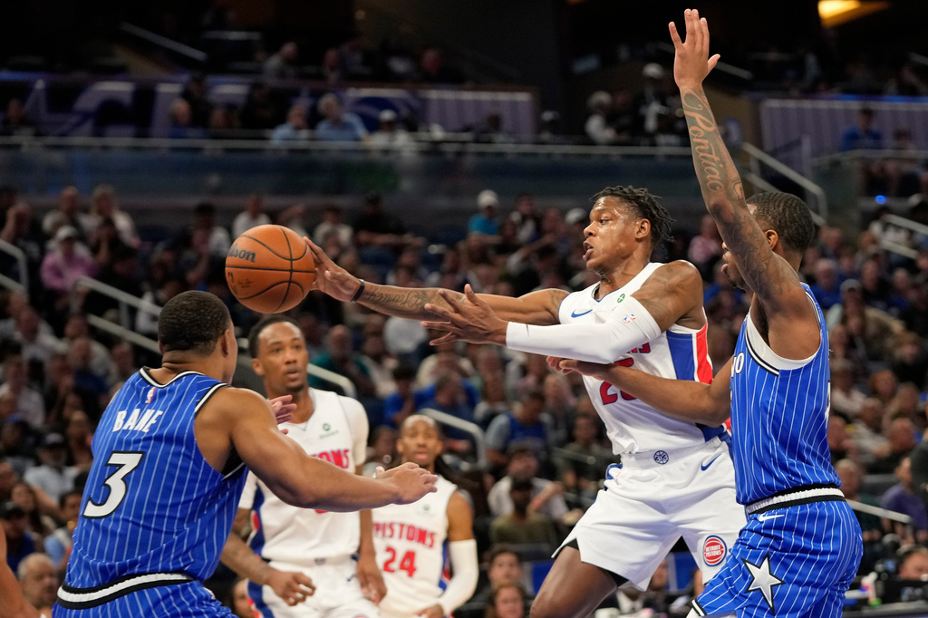 Detroit Pistons guard Marcus Sasser, center, passes the ball as he gets between Orlando Magic guard Desmond Bane (3) and forward Jamal Cain during the first half of an NBA basketball game, Monday, April 6, 2026, in Orlando, Fla. (AP Photo/John Raoux)