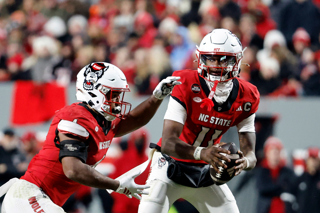 FILE - North Carolina State quarterback CJ Bailey (11) hands the ball off to running back Jayden Scott (4) during the second half of an NCAA college football game in Raleigh, N.C., Nov. 29, 2025. (AP Photo/Karl DeBlaker, File)