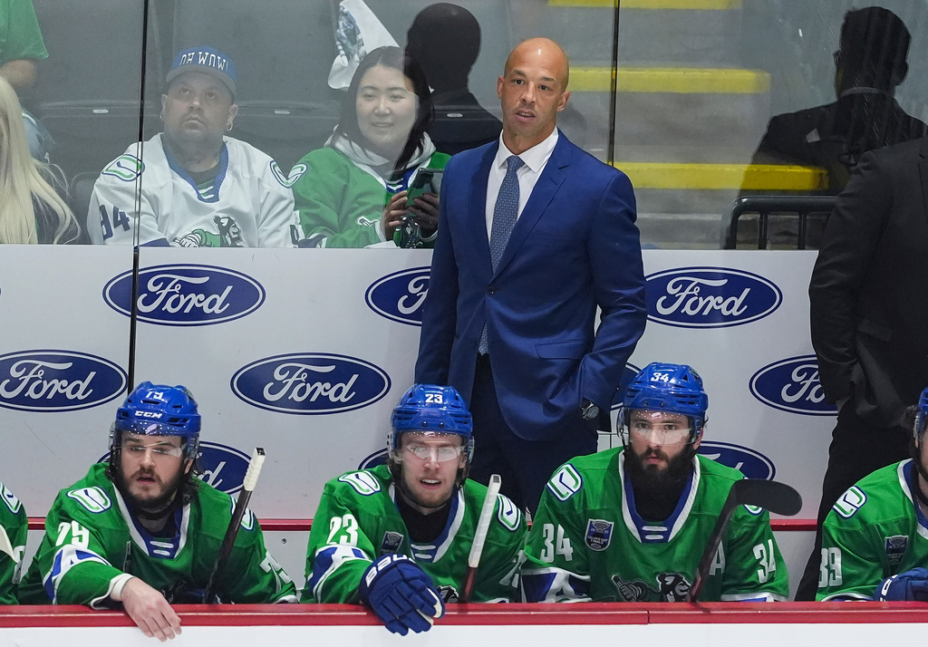 FILE -Abbotsford Canucks' head coach Manny Malhotra stands on the bench behind Sammy Blais, front left to right, Jonathan Lekkerimaki and Phillip Di Giuseppe during the first period in Game 5 of the AHL hockey Calder Cup Final against the Charlotte Checkers, in Abbotsford, British Columbia, June 21, 2025. (Darryl Dyck/The Canadian Press via AP, File)