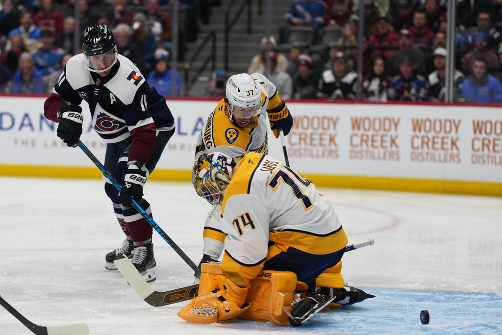 Colorado Avalanche center Brock Nelson, left, shoots past Nashville Predators goaltender Juuse Saros (74) and defenseman Nick Blankenburg (37) for a goal in the first period of an NHL hockey game Friday, Jan. 16, 2026, in Denver. (AP Photo/David Zalubowski)