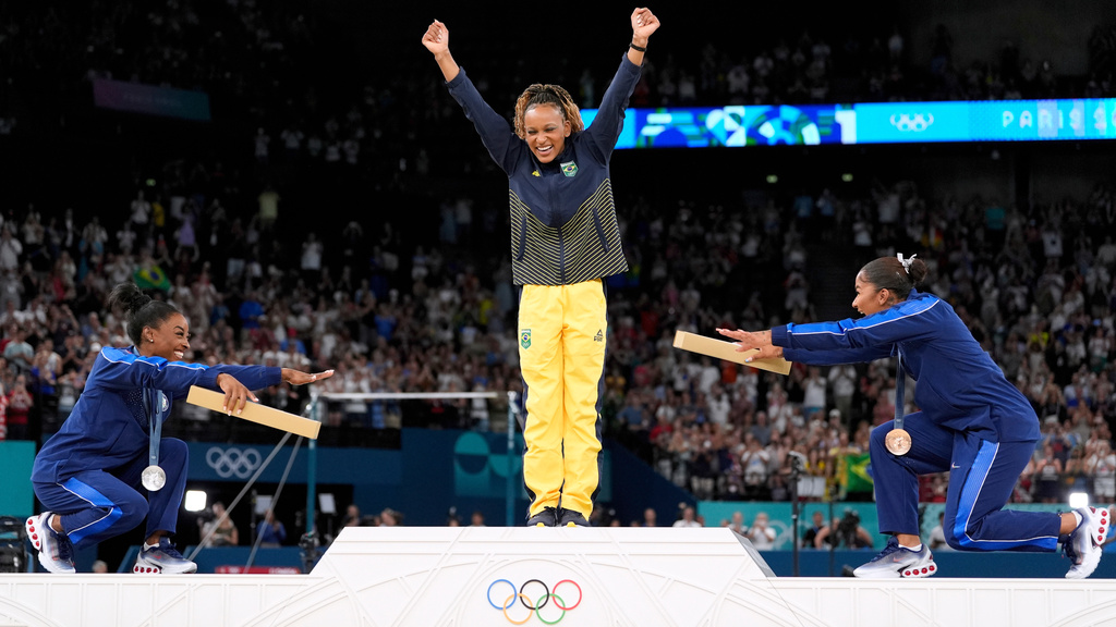 FILE - Silver medalist Simone Biles, of the United States, left, and bronze medalist Jordan Chiles, of the United States, right, bow to gold medalist Rebeca Andrade, of Brazil, during the medal ceremony for the women's artistic gymnastics individual floor finals at Bercy Arena at the 2024 Summer Olympics, Aug. 5, 2024, in Paris, France. (AP Photo/Abbie Parr, File)