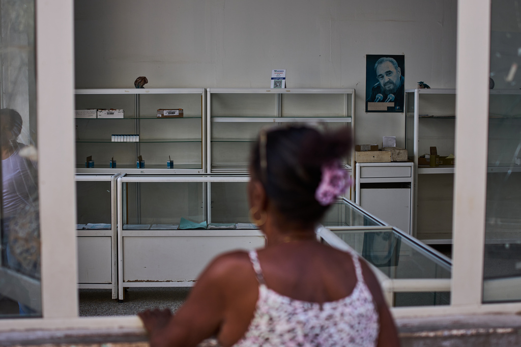 An image of Fidel Castro hangs on the wall of a state-run pharmacy where a woman asks for medication in Havana, Cuba, Wednesday, July 29, 2026. (AP Photo/Ramon Espinosa)
