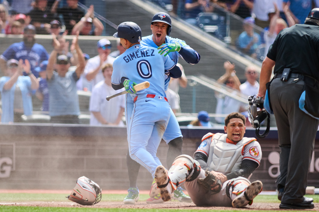 Toronto Blue Jays' Andrés Giménez (0) celebrates with George Springer, second from left, after scoring on a single hit by Nathan Lukes (not shown) against the Baltimore Orioles during sixth-inning baseball game action in Toronto, Sunday, June 7, 2026. (Sammy Kogan/The Canadian Press via AP)