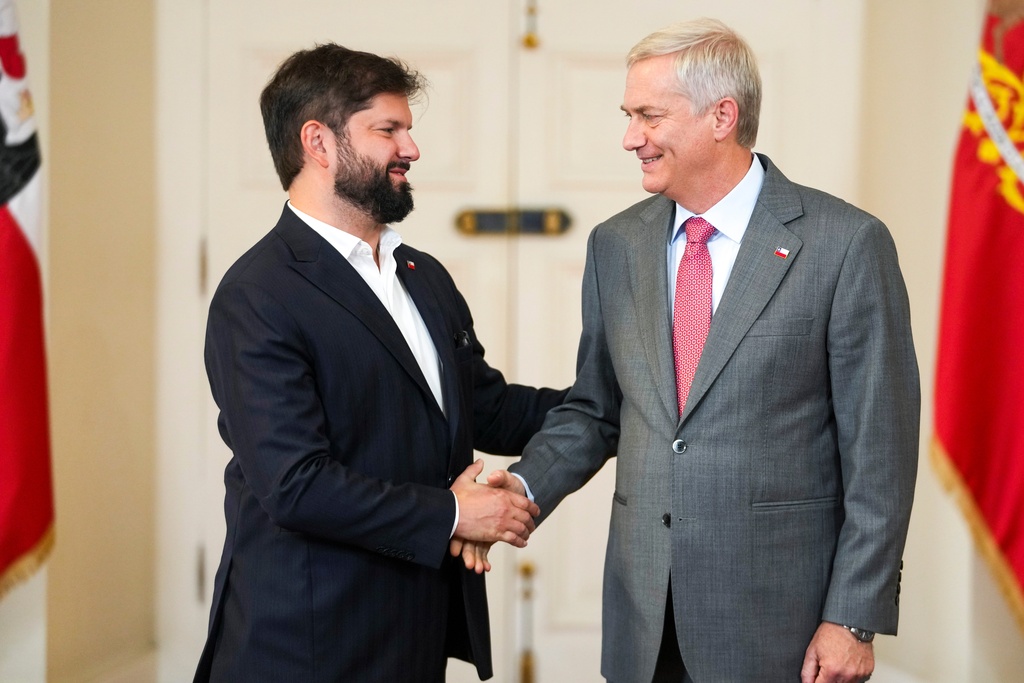 Chilean President Gabriel Boric, left, welcomes President-elect Jose Antonio Kast to La Moneda palace the day after Kast won the presidential election runoff in Santiago, Chile, Monday, Dec. 15, 2025. (AP Photo/Esteban Felix)