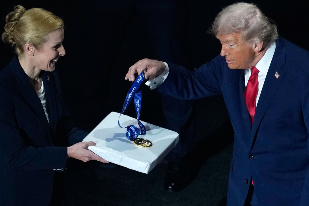 President Donald Trump picks up his FIFA Peace Prize medal, awarded to him by FIFA President Gianni Infantino, before the draw for the 2026 soccer World Cup at the Kennedy Center in Washington, Friday, Dec. 5, 2025. (AP Photo/Julia Demaree Nikhinson)