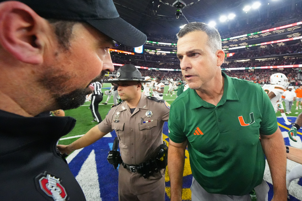 Miami head coach Mario Cristobal, right, and Ohio State head coach Ryan Day talk following the Cotton Bowl College Football Playoff quarterfinal game Wednesday, Dec. 31, 2025, in Arlington, Texas. (AP Photo/Julio Cortez)