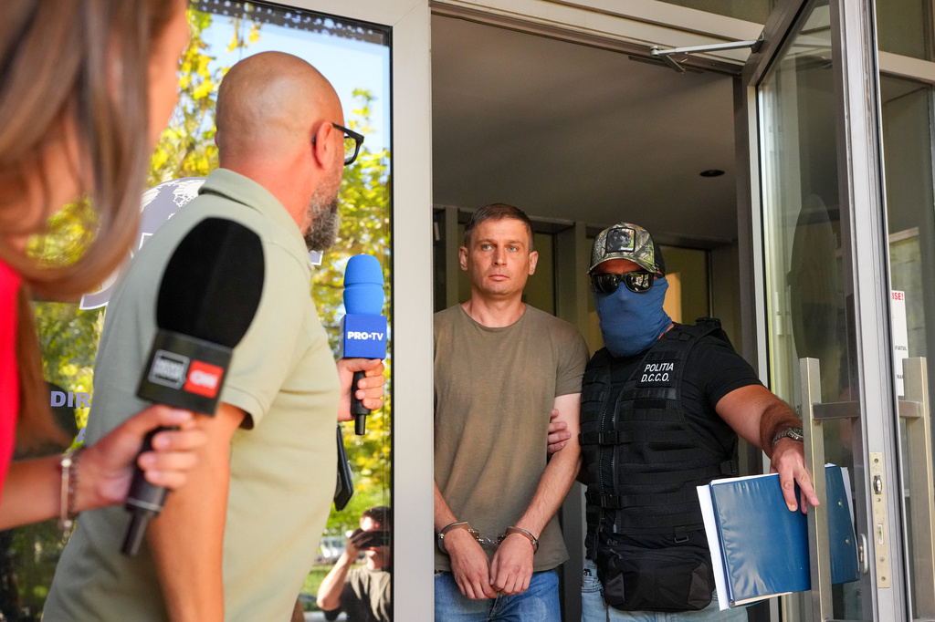 Police officers escort a Russian citizen investigated for committing the crime of attempted sabotage after he was detained by prosecutors from Romania's Directorate for Investigating Organised Crime and Terrorism, DIICOT, in Bucharest, Romania, Tuesday, Sept. 8, 2026. (AP Photo/Vadim Ghirda)