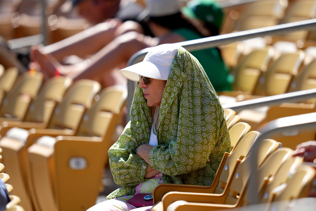 A baseball fan tries to shield from the sun during the fourth inning of a spring training baseball game between the Chicago White Sox and the Athletics, Tuesday, March 17, 2026, in Phoenix. (AP Photo/Ross D. Franklin)